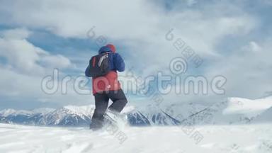 男子背着背包站在雪山顶上，胜利者摆姿势，举起双手欣赏风景和成就